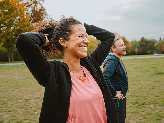 Woman in pink standing outside hands on head smiling